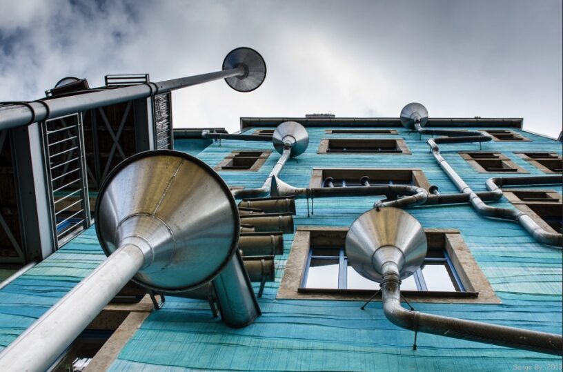 An upward perspective of a modern building with distinctive tubular architecture against a cloudy sky.