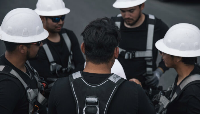 A team of construction workers in safety gear engaging in a discussion on a work site.