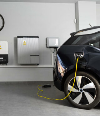 An electric vehicle charging in a modern home garage with a bike mounted on the wall.