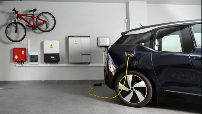 An electric vehicle charging in a modern home garage with a bike mounted on the wall.