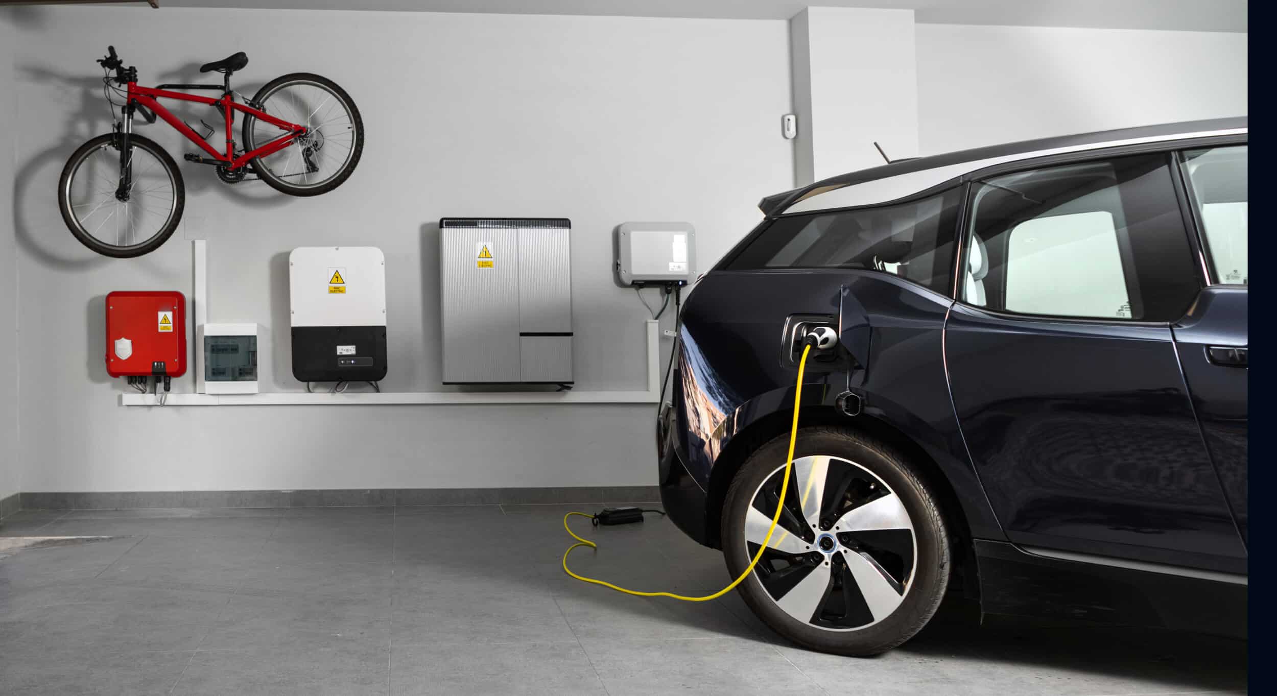 An electric vehicle charging in a modern home garage with a bike mounted on the wall.