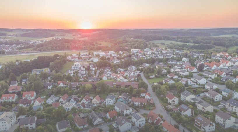 A serene sunset over a tranquil suburban town, bathed in warm hues as the day draws to a close.