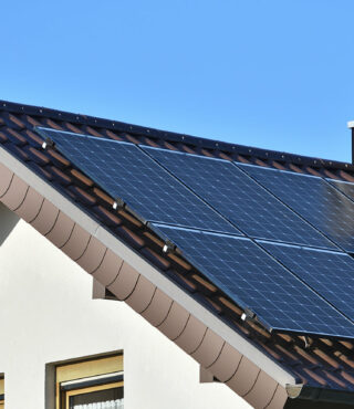 Solar panels on a residential rooftop against a clear blue sky, showcasing renewable energy in a domestic setting.