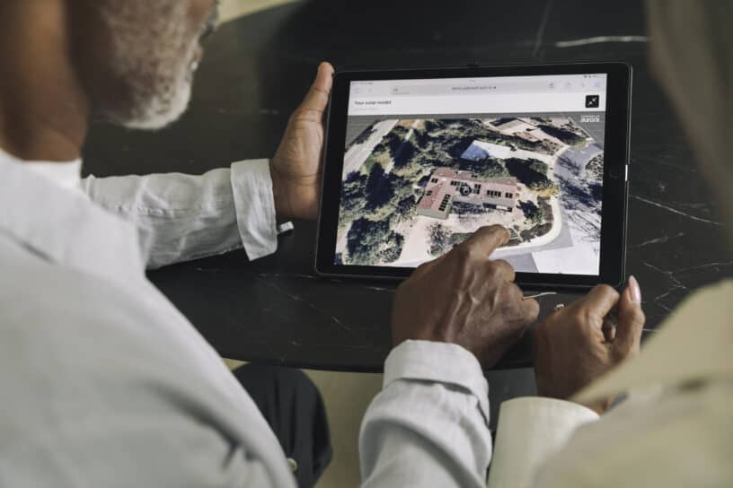 Two individuals examining an aerial view of a property on a tablet screen