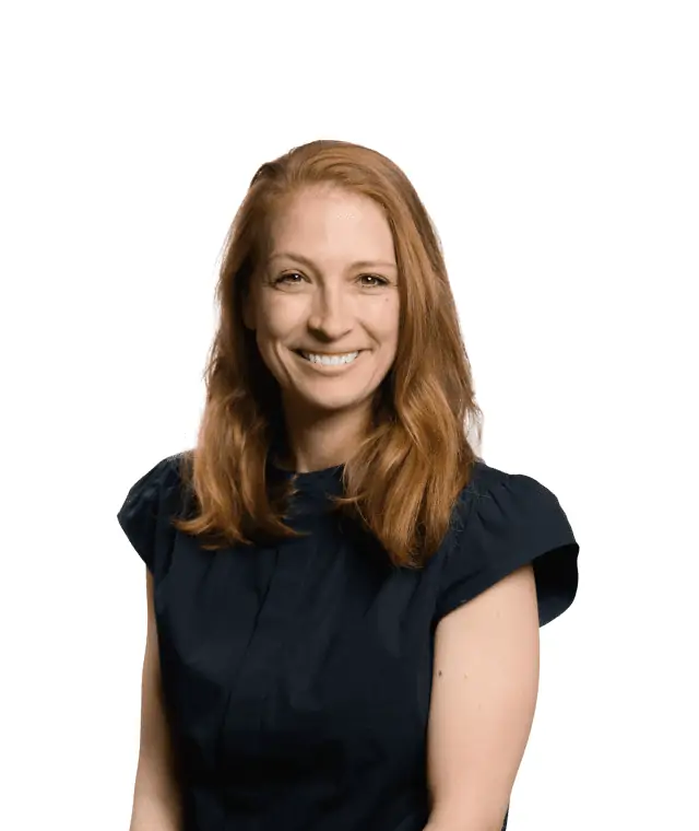 A smiling woman with long red hair wearing a dark blouse against a white background.