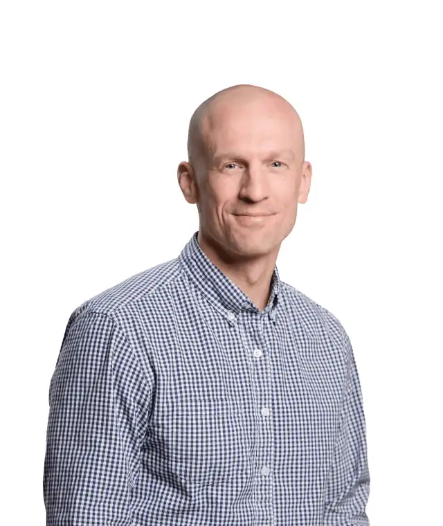 A confident man with a friendly smile, wearing a blue checkered shirt, posing against a white background.