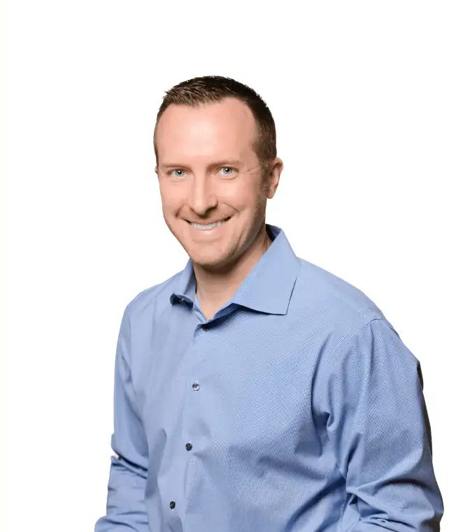 Professional man in a blue shirt smiling confidently against a white background.