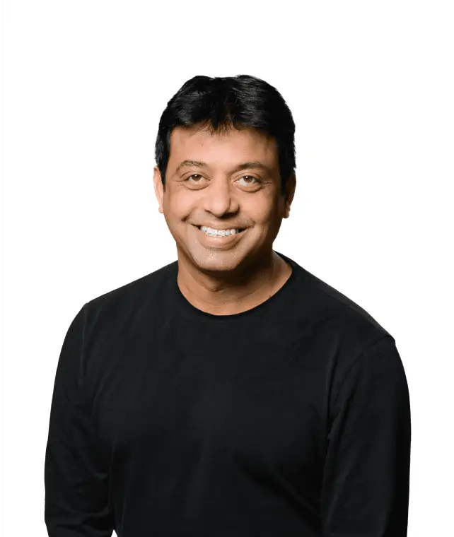 A cheerful man with a friendly smile, wearing a black shirt against a white background.