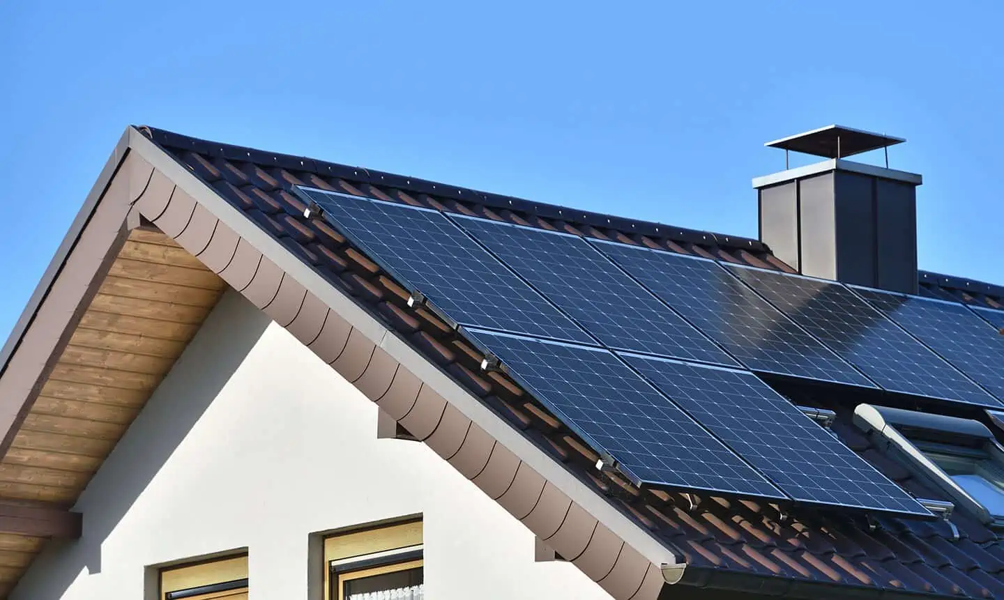 Solar panels on a residential rooftop against a clear blue sky, showcasing renewable energy in a domestic setting.